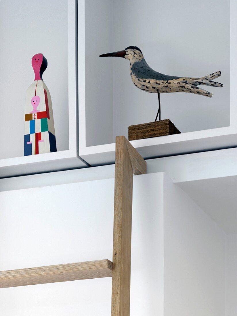Vogelfigur und moderne bemalte Figur im weissen kubischen Regal