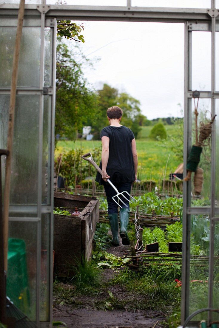 Frau bei der Gartenarbeit mit einem Spatengabel in der Hand