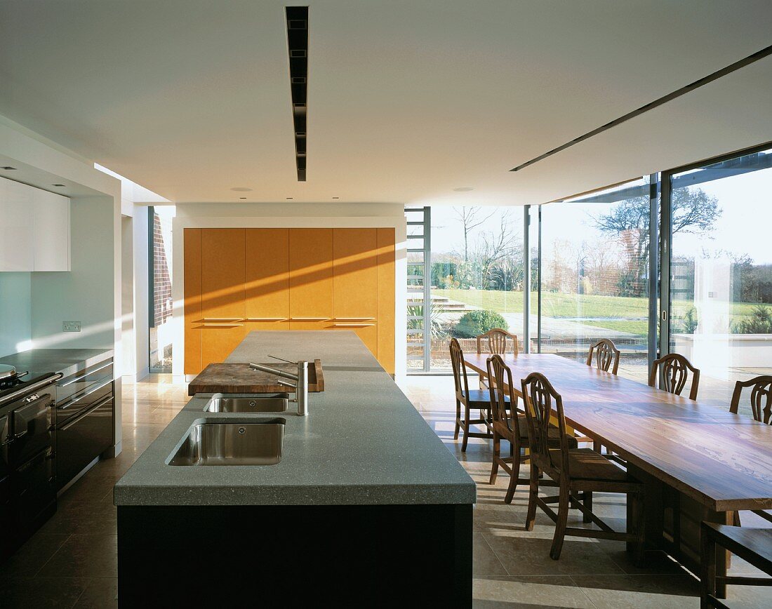 Offener moderner Wohnraum mit Kochbereich und Essplatz mit antiken Holzstühlen
