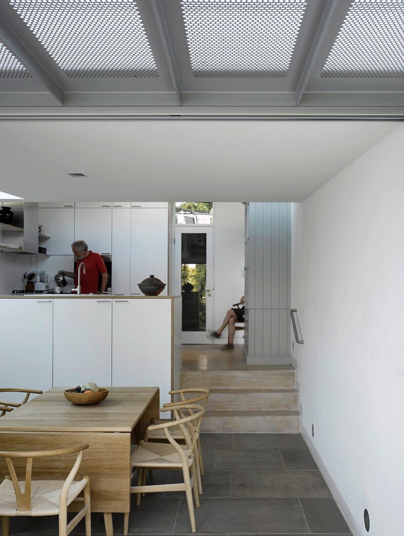 Offener Wohnraum mit Essplatz vor Küche und breitem Durchgang mit Stufen