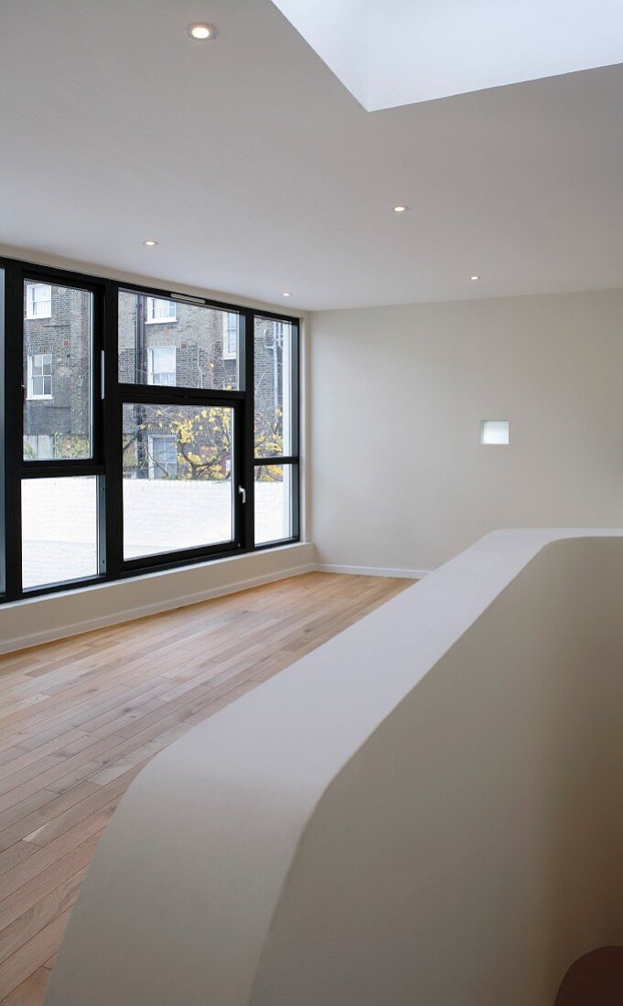 Empty living room with recessed downlights and large window in a contemporary building