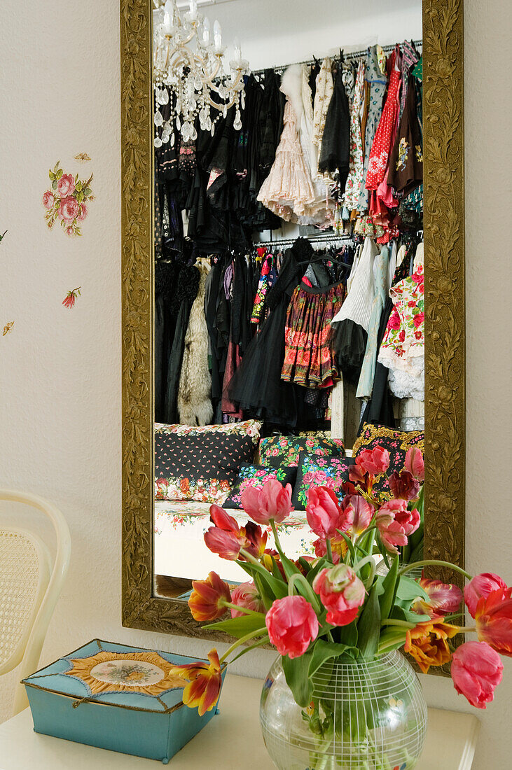 Mirror with gold-coloured frame and bouquet of tulips on chest of drawers