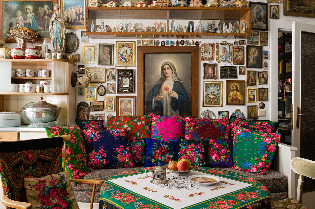 Room with religious pictures and figures, sofa with floral cushions