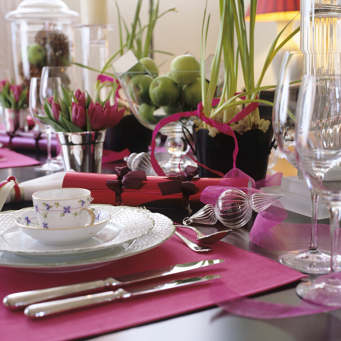 Festlich gedeckter Tisch mit Tulpen, grünen Äpfeln und Tischsets in Pink