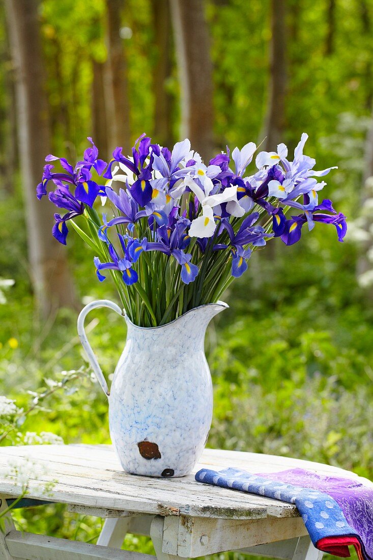 Blue and white irises in a jug on a wooden table