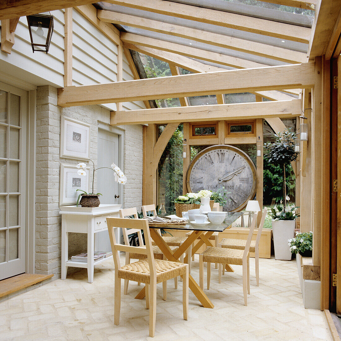 Conservatory with dining table, large clock, wooden furniture and glass roof