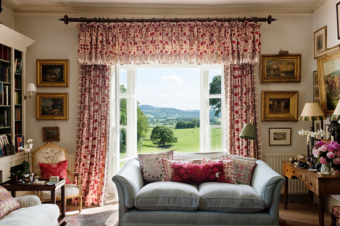 Country-style living room with patterned curtains and countryside views