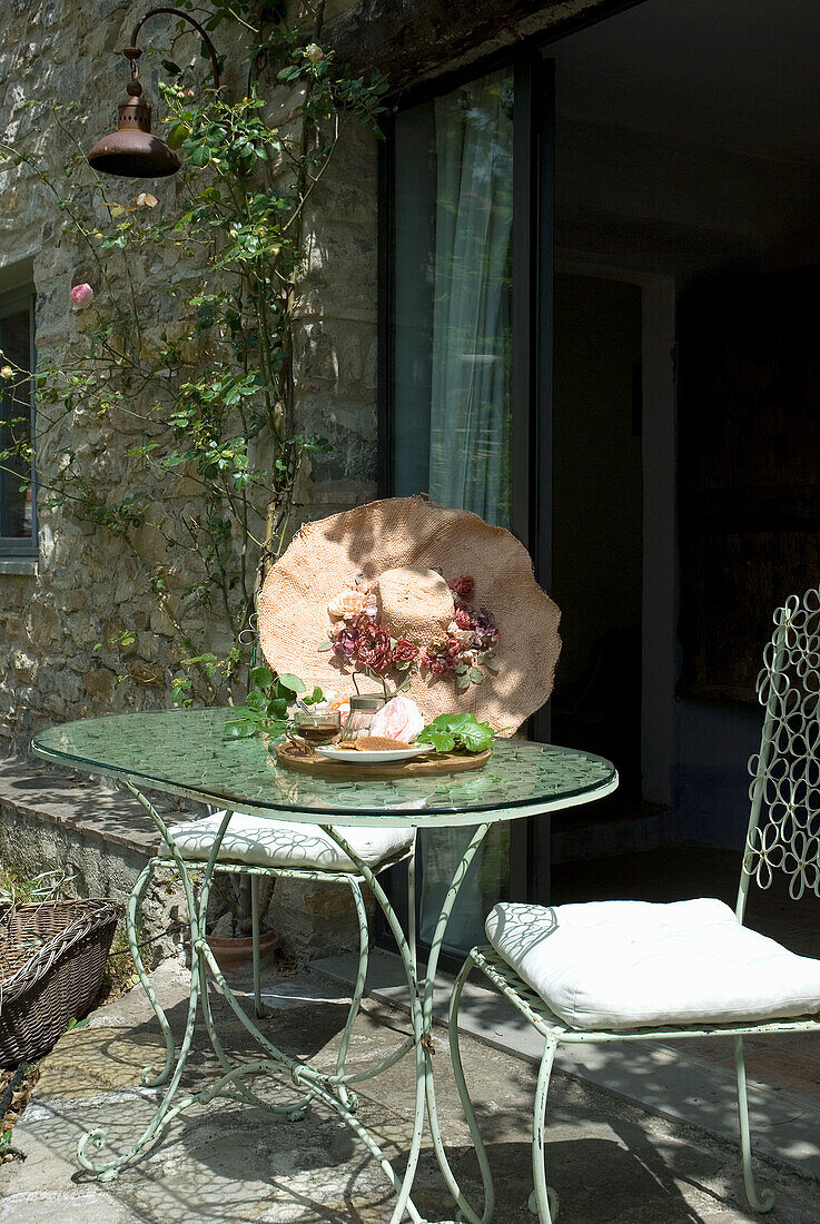 Metal patio table with decoration and stone façade in the background