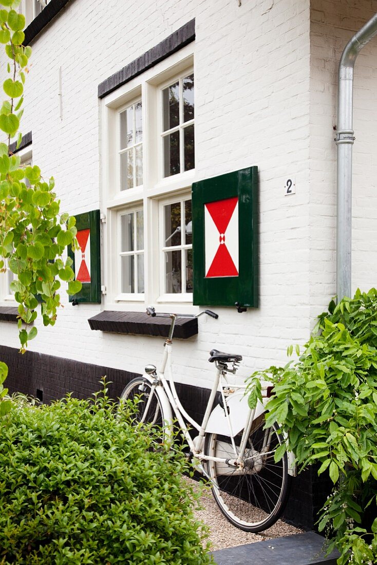 Dutch bicycle leaning against white brick facade with unusually painted shutters