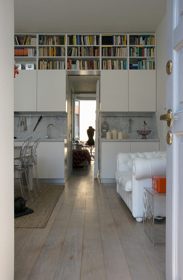 Modern, white kitchen with bookshelf and adjoining dining area