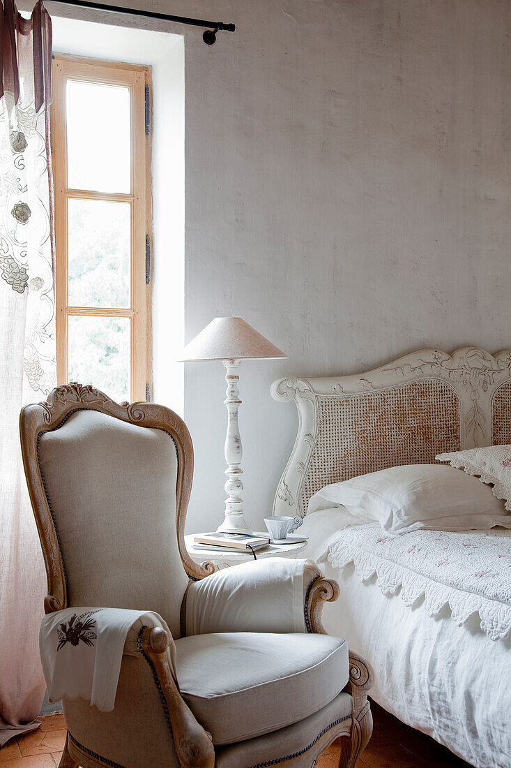 Romantic bedroom with vintage bed and upholstered armchair