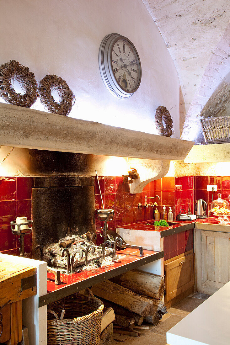 Rustic country kitchen with open fireplace and red tiles on the wall