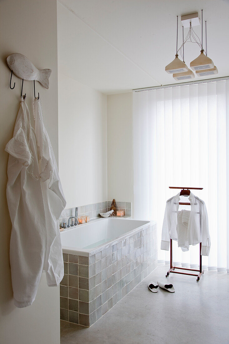 Minimalist bathroom with tiled bathtub and clothes horse