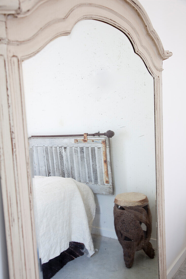 African stool and radiator are reflected in the vintage-style mirror