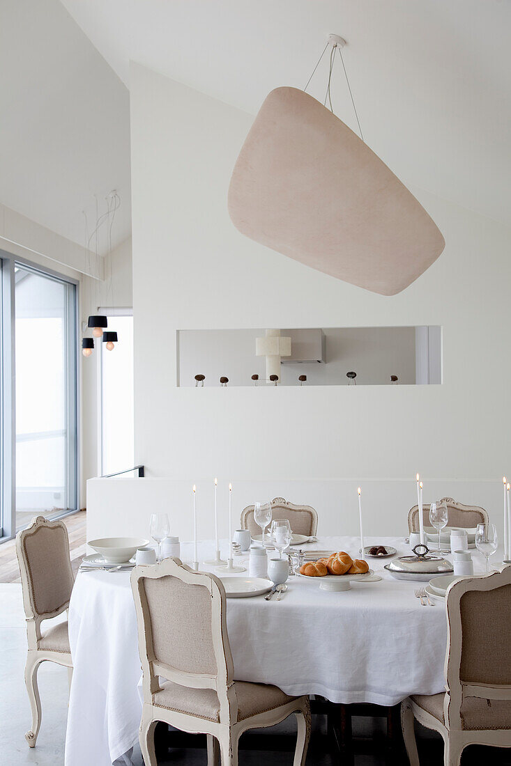 Bright dining room with white table, classic chairs and designer lamp