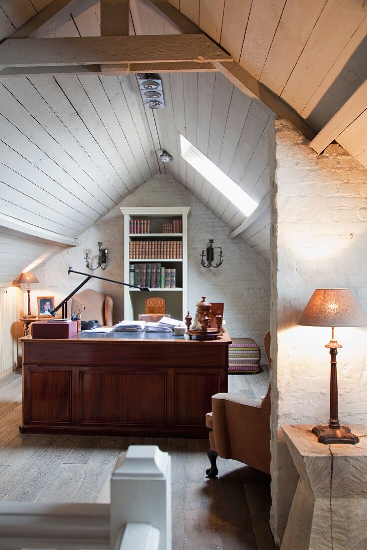 Open-plan workspace with solid wooden desk in rustic attic interior