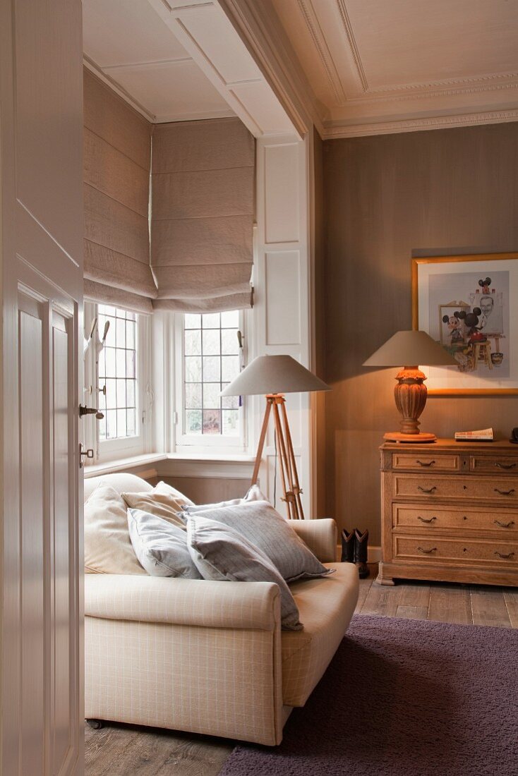 View through open door of sofa with scatter cushions in rustic interior