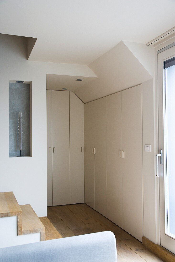 Raumecke mit eingebauten Schränken und Treppenaufgang in moderner Maisonette-Wohnung im skandinavischen Stil