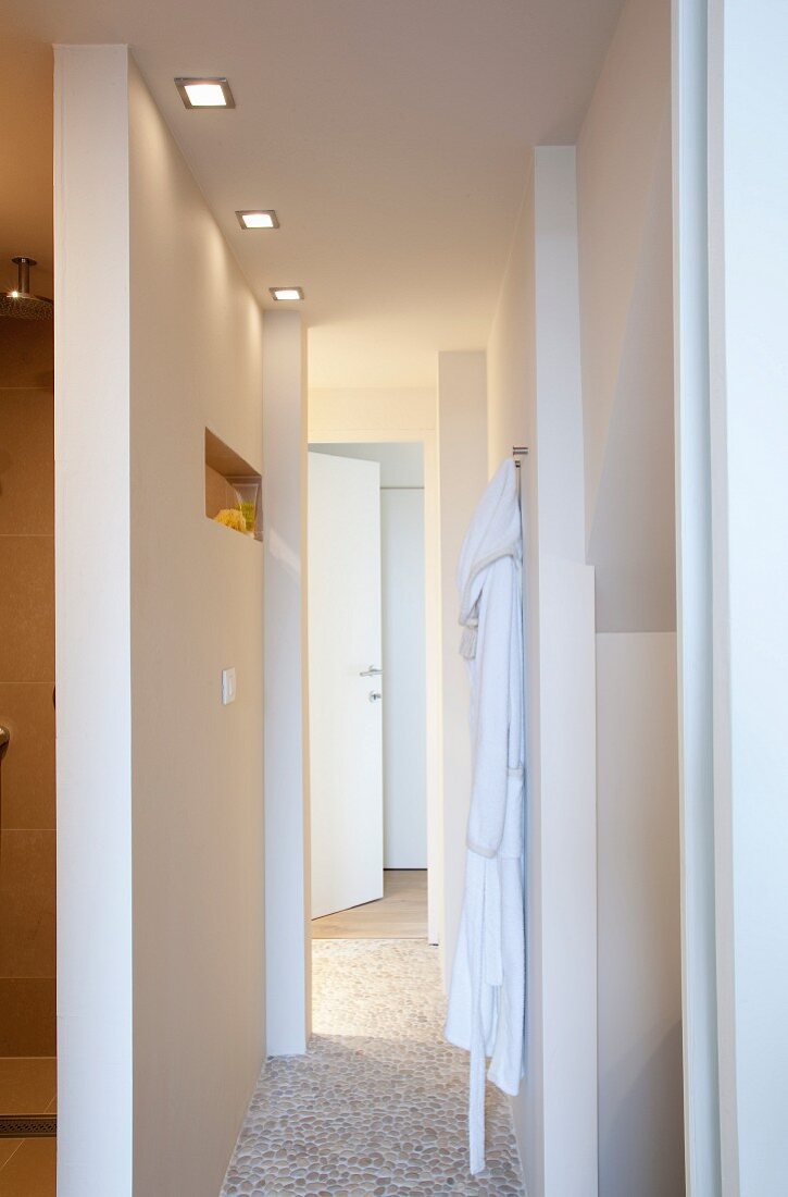 Türen und Durchgänge in der Gangflucht eines Badezimmers mit Mosaikboden in Kieseloptik