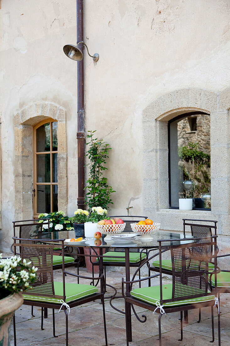 Terrace corner with metal furniture and potted plants in front of a historic wall