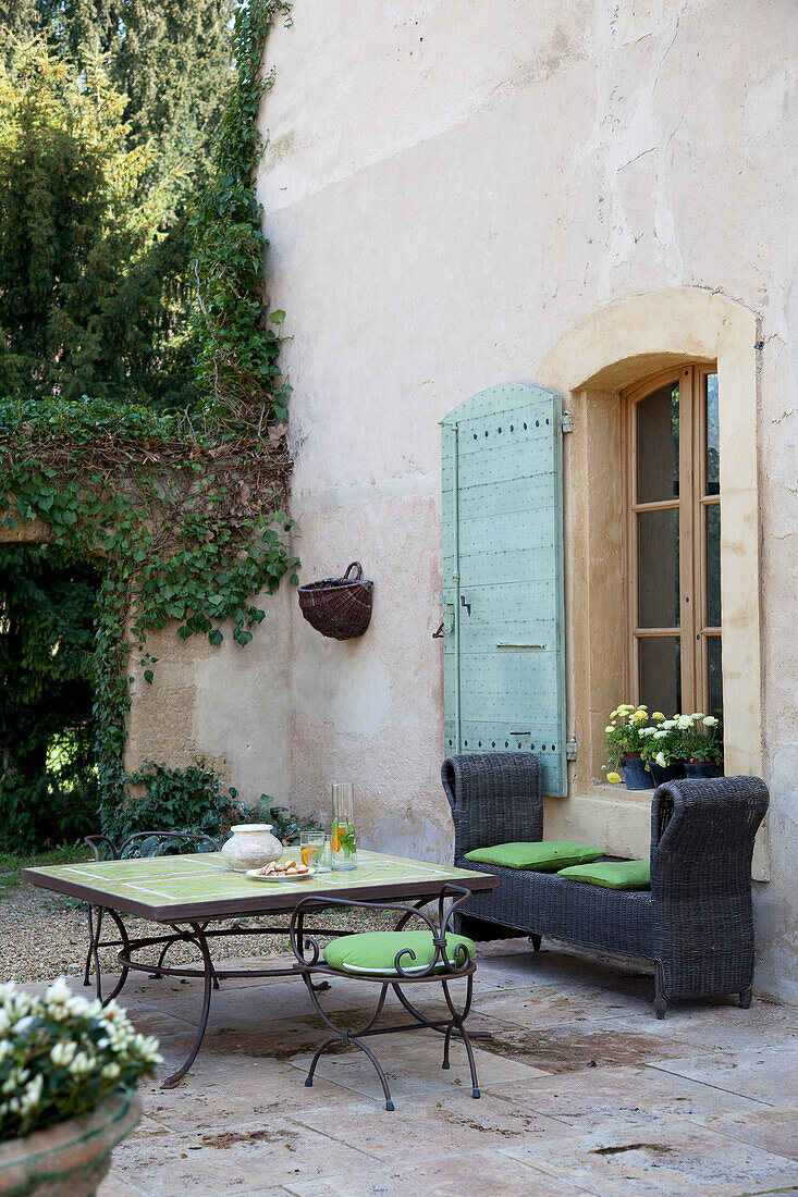 Seating area with green cushions in front of historic house wall in the garden