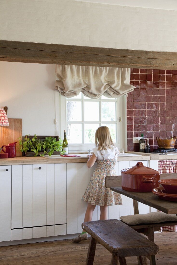 Girl standing in front of counter in rustic, country-house kitchen