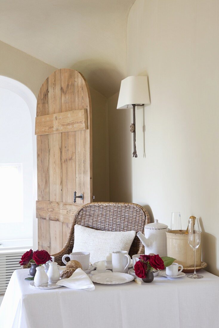 Set breakfast table with flowers in front of open wooden door in simple room