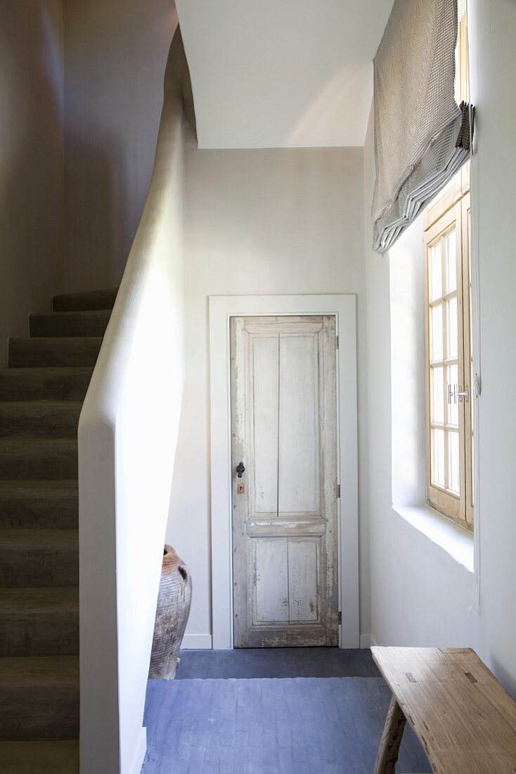 Simple stairwell with blue-painted floor and rustic interior door