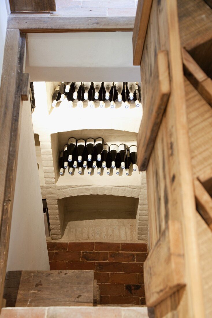 Blick durch offene Kellerluke auf Weinregal aus geweisselten Ziegelsteinen