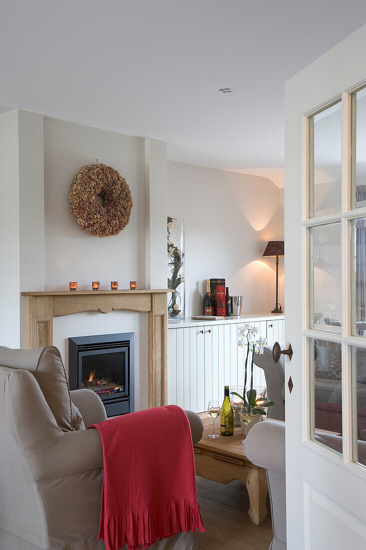 Living room with fireplace, red blanket over the armchair and decorative wall wreath