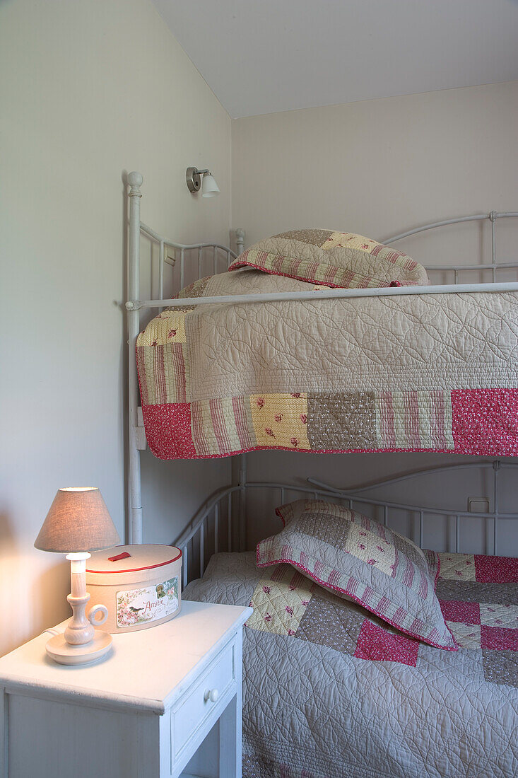 Bunk bed with patchwork bed linen and bedside lamp in the children's room