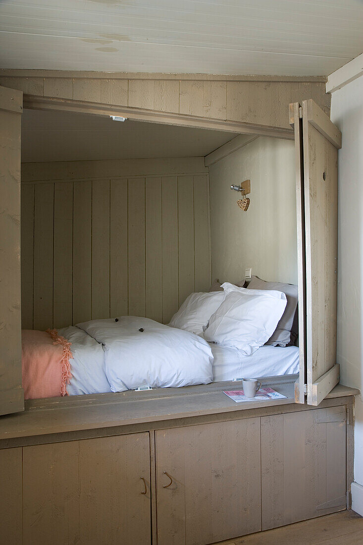 Built-in bed with storage space in an alcove with wood panelling