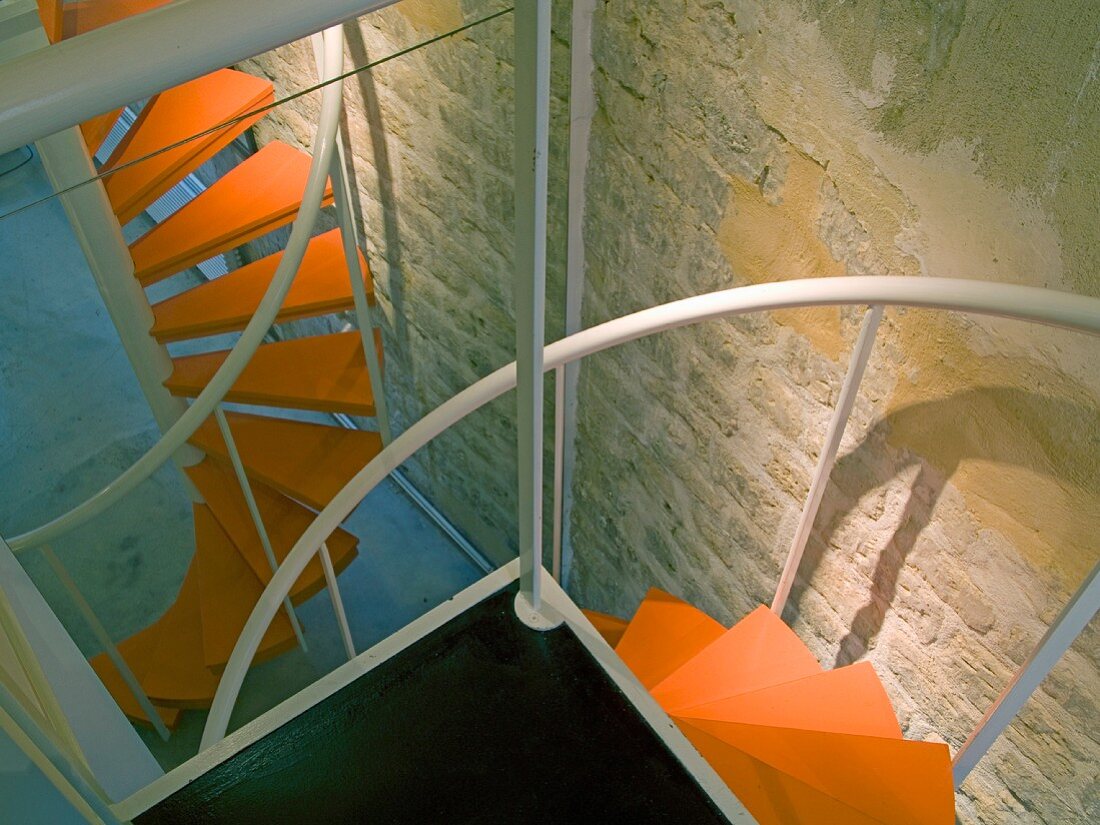 Wendeltreppe mit orangefarbenen Stufen in einer Loftwohnung