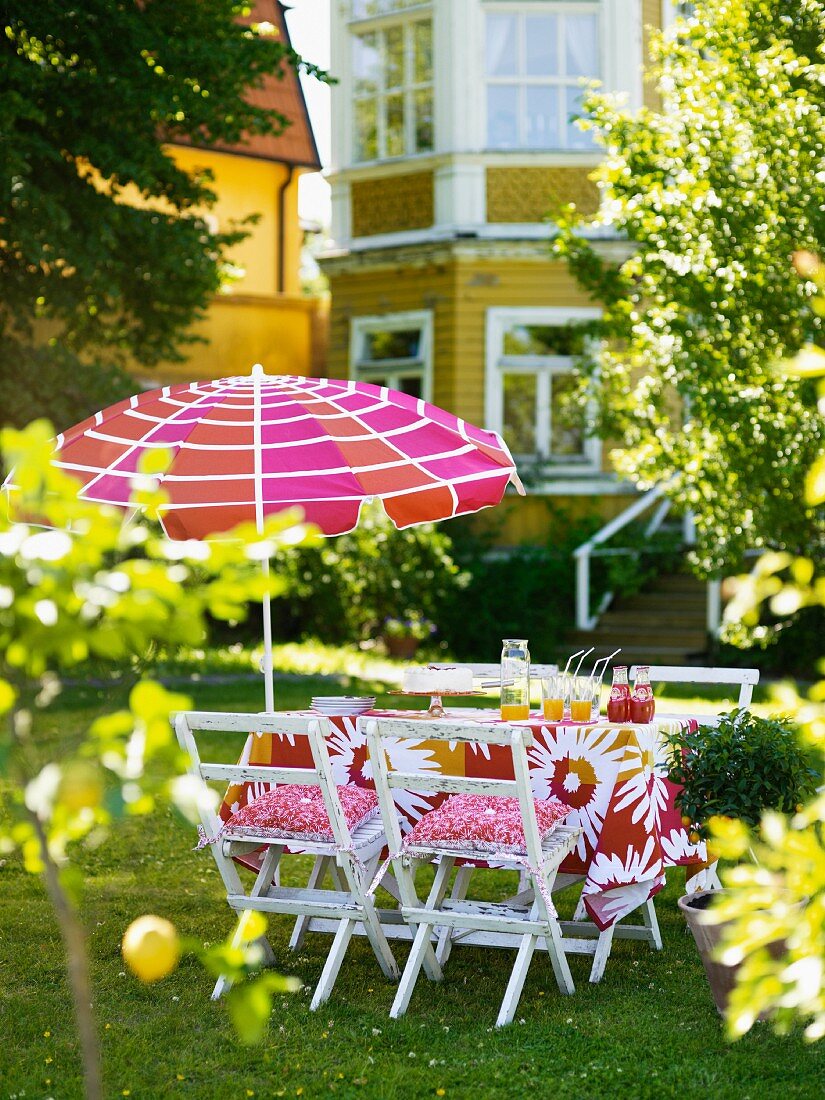 Sommerlicher Gartentisch mit Sonnenschirm vor einem Haus