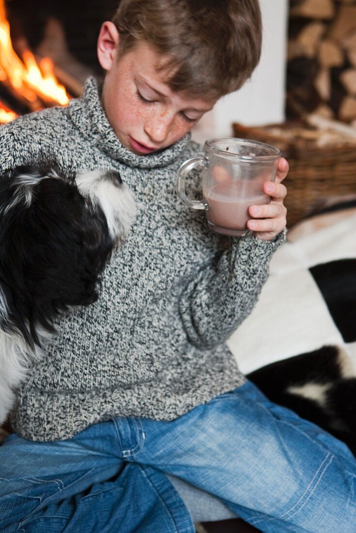 Junge mit Hund trinkt Kakao