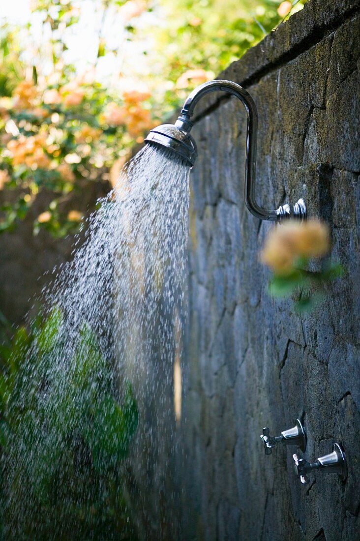 Dusche an Steinmauer im Garten