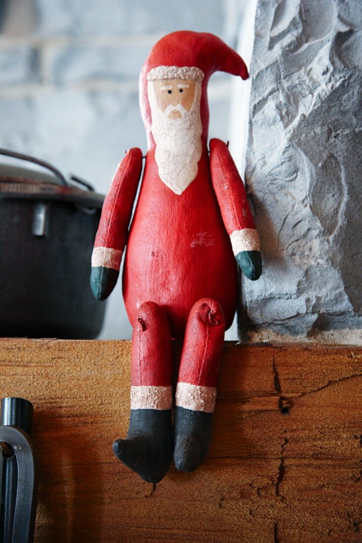 Weihnachtsmann aus Holz sitzt auf dem Kaminsims