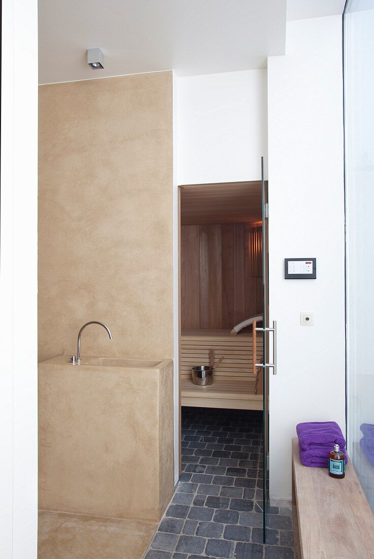 Washstand in sand-coloured concrete and grey cobbled floor in modern bathroom