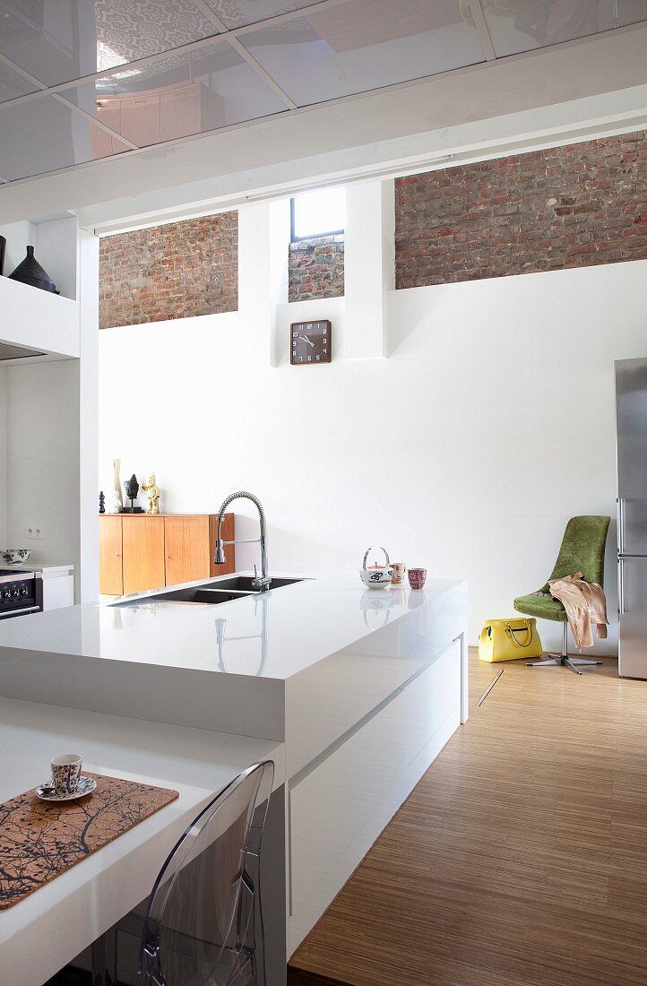White designer kitchen in loft apartment with exposed brick elements in white, rendered wall