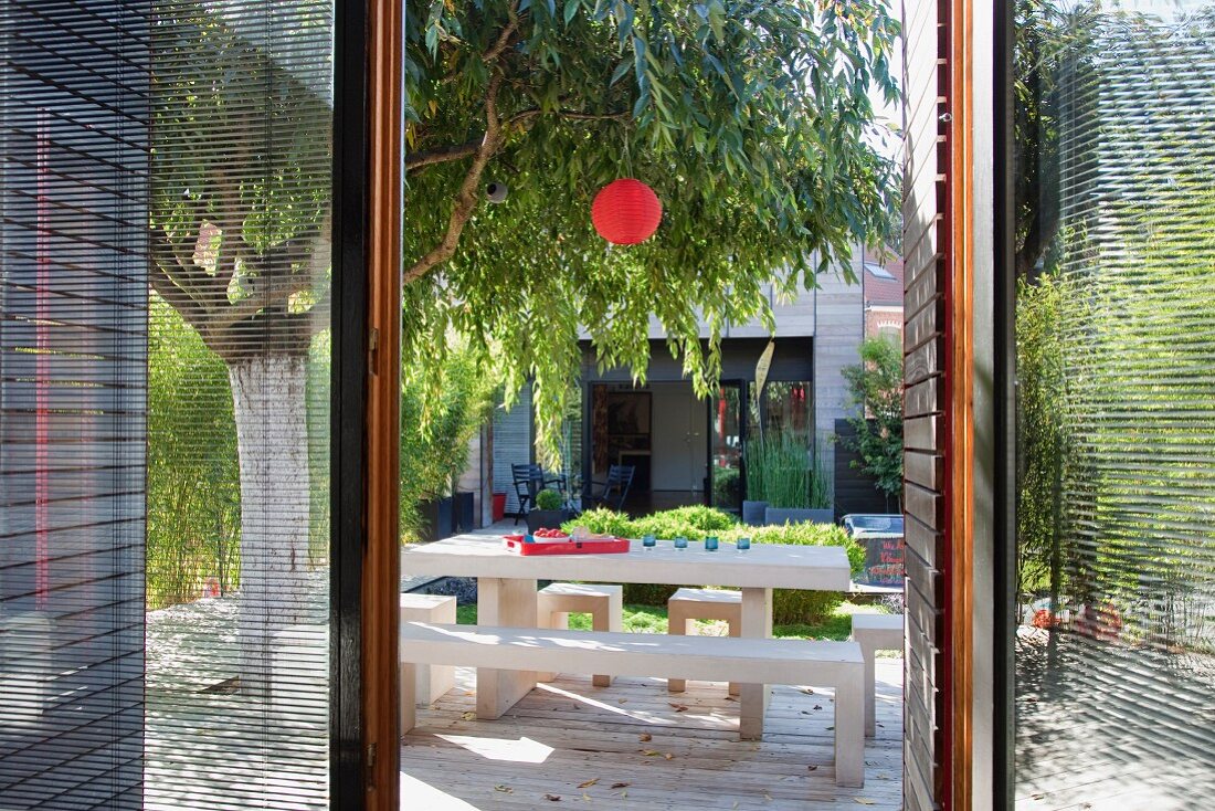 Blick durch offene Terrassentür auf Designer Tisch- und Bankgarnitur