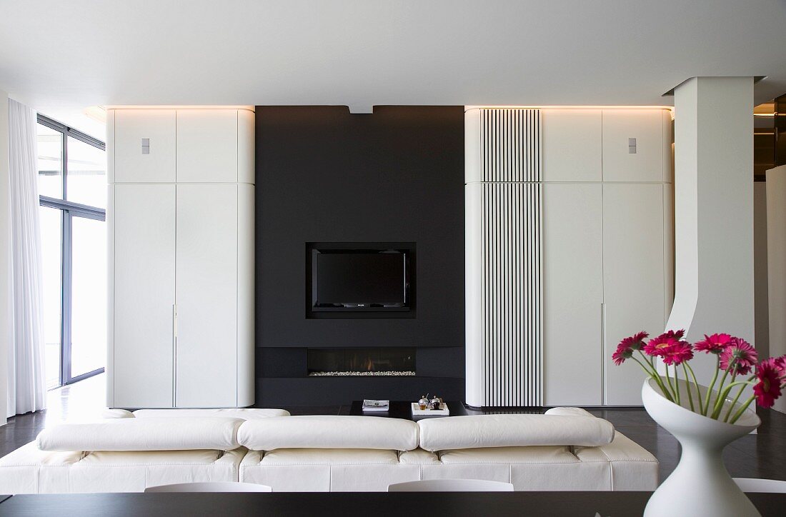 Designer-Wohnzimmer - weiße Faltwand vor schwarzer Einbaufront mit Kamin und TV