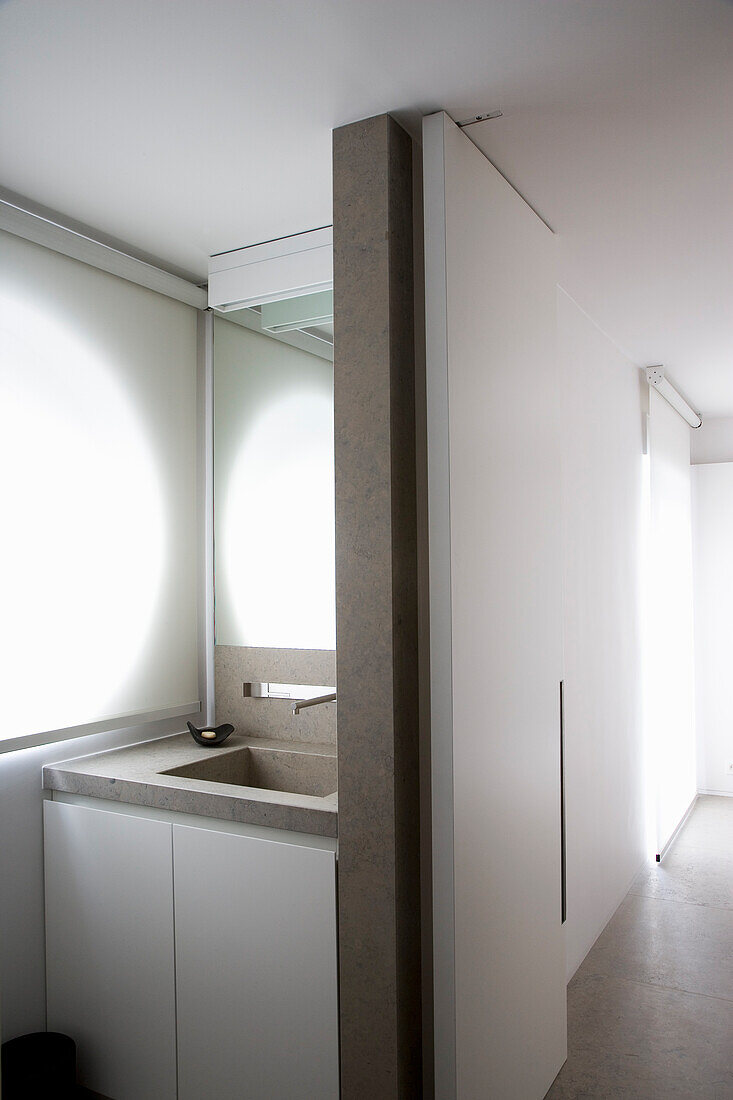 Schmales, modernes Badezimmer mit Betonwaschtisch und weißen Rollos