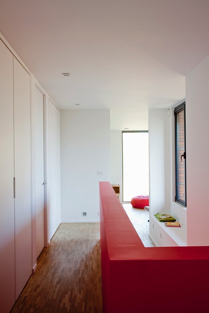Red, half-height wall on landing with parquet floor
