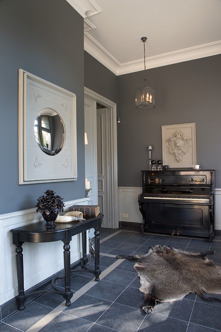 Blue-grey interior in renovated period building with antique furniture and animal-skin rug on tiled floor