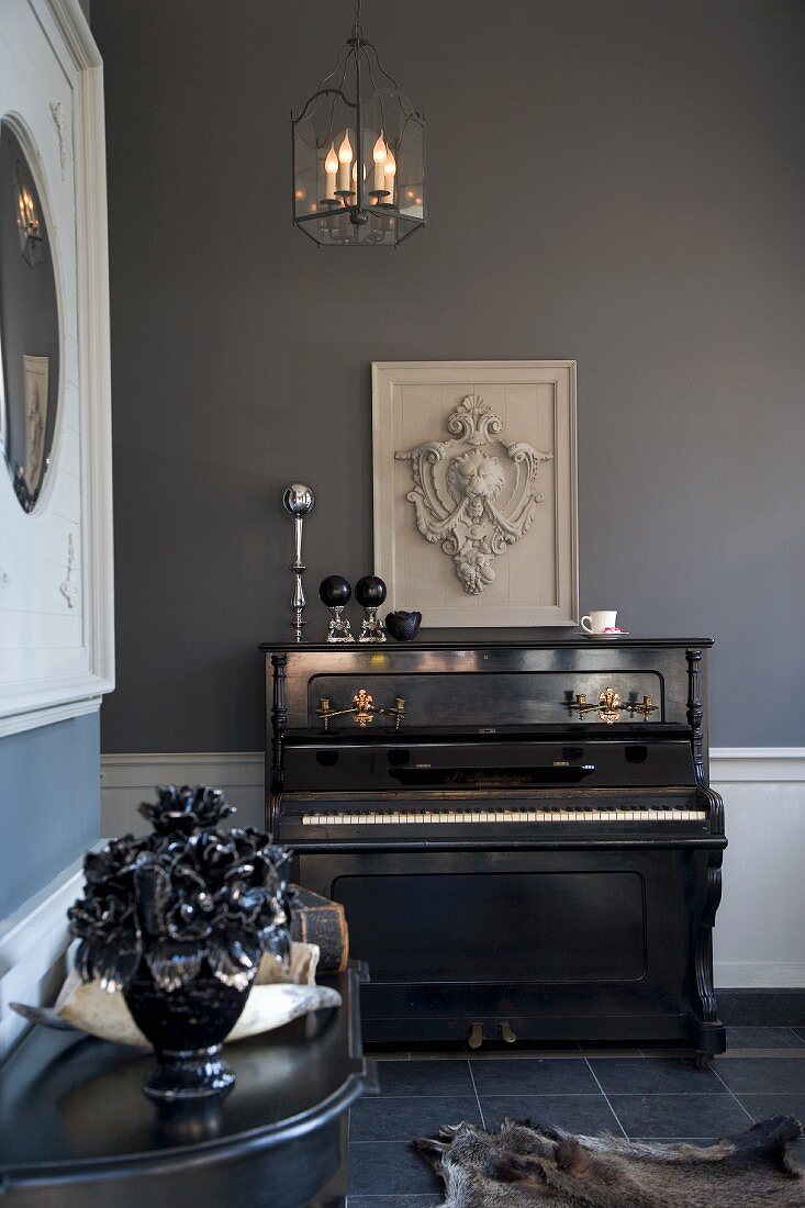 Blue-grey interior in renovated period building with coat of arms relief above antique piano