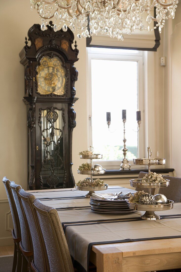 Modern dining area with magnificent, antique long-case clock and silver cake stands on table