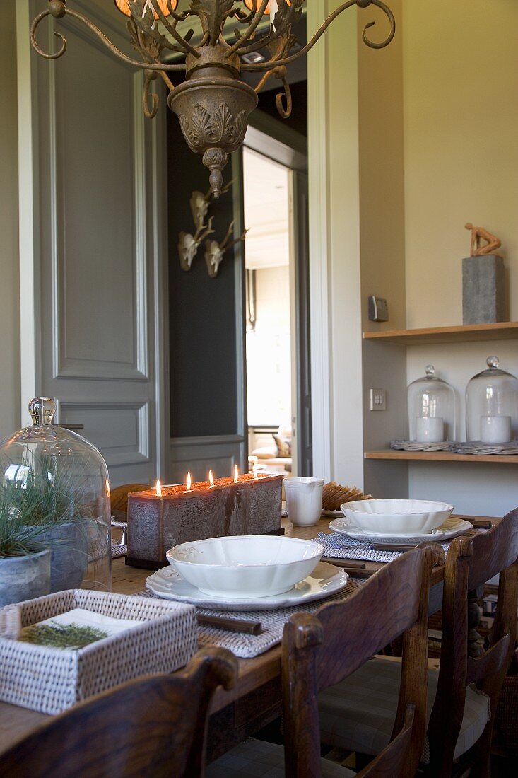 Mit Kerzenblock festlich gedeckter Tisch unter Antik-Kronleuchter in unkonventioneller Landhaus-Küche
