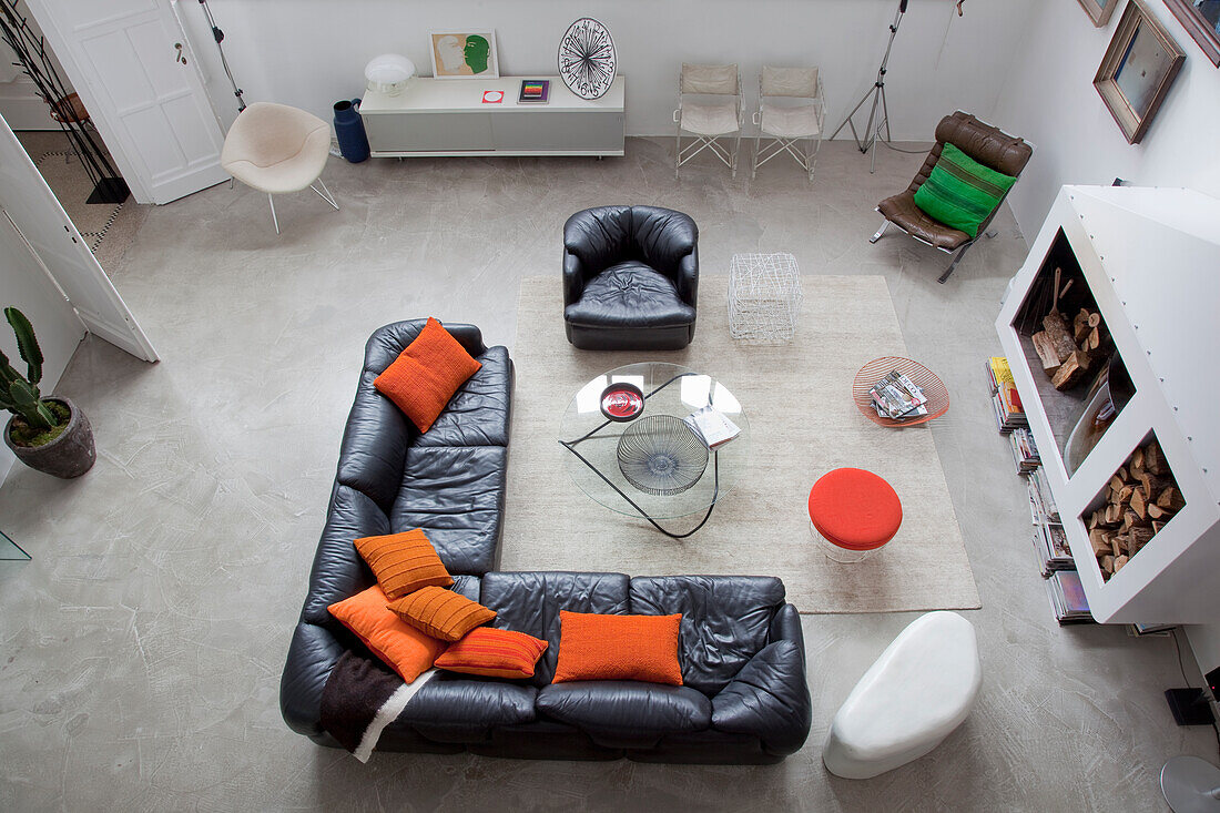 Living room with L-shaped leather sofa, orange-coloured cushions and fireplace