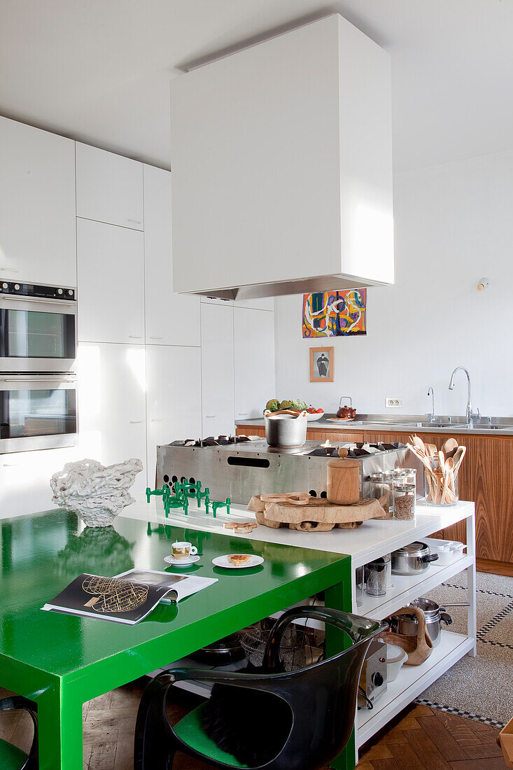 Modern kitchen unit with green dining table and stainless steel appliances