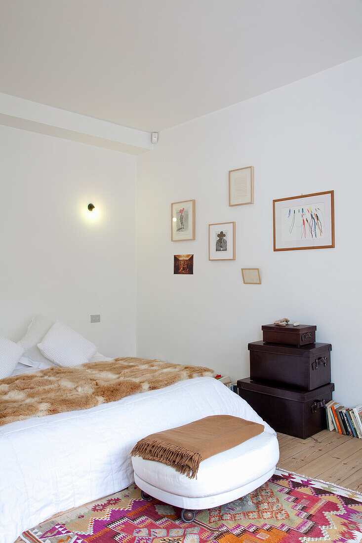 Bedroom with white bed linen, fur-look throw and colourful ethnic rug